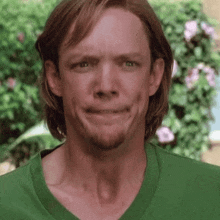 a man wearing a green shirt making a funny face