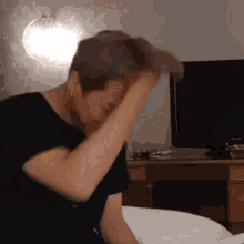 a man is sitting on a bed with his head in his hand .