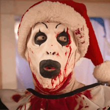 a bloody clown wearing a santa hat and a white mask