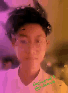 a man wearing glasses and a white shirt has a foreign language written on his chest