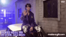 a young man in a purple coat is sitting on a car and waving .