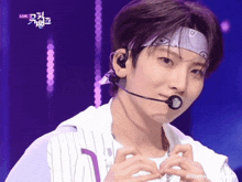 a young man is wearing a headband and a microphone while standing on a stage .