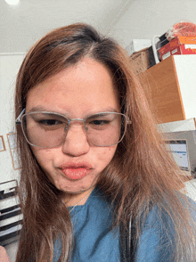 a woman wearing glasses and a blue shirt makes a face