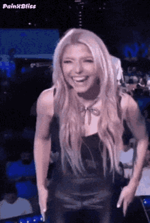 a woman with long blonde hair is laughing while wearing a black top .