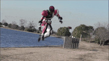 a person in a robot costume jumps in the air near a body of water