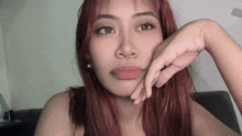 a woman with red hair is looking at the camera with her hand on her chin