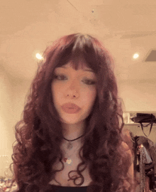 a woman with long curly red hair is wearing a choker and a necklace