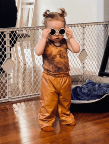a little girl wearing sunglasses is standing in front of a dog bed