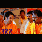 a group of men wearing orange shirts and yellow scarves are standing in a line .