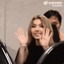 a woman is waving at a man while sitting in a chair .