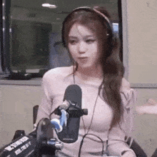 a woman is wearing headphones and sitting in front of a microphone .
