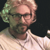 a man wearing glasses and a wig is sitting in front of a microphone