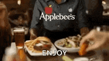 a person is sitting at a table with plates of food and a glass of beer .