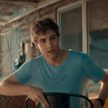a young man in a blue shirt sits on a chair