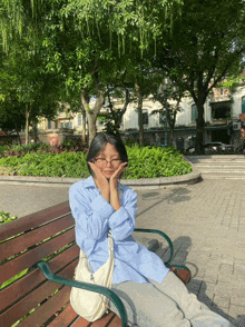 a woman sits on a bench with her hands on her face in front of a building that says ' a ' on it