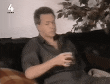 a man sitting on a couch holding a glass with the number 4 on the bottom