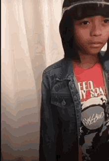 a young boy wearing a denim jacket and a red t-shirt with the word dub on the front