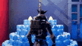 a video game character is standing in front of a large blue cake