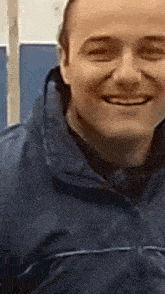 a close up of a man wearing a blue jacket smiling .