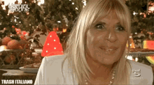 a woman with blonde hair is smiling in front of a christmas tree with the words trash italiano on the bottom