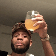a man in a hat is holding a glass of beer