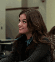a woman with long dark hair is smiling in a room
