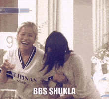 two women are laughing and one of them is wearing a shirt that says bbs shukla