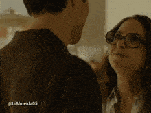 a man and a woman are looking at each other and the woman has glasses