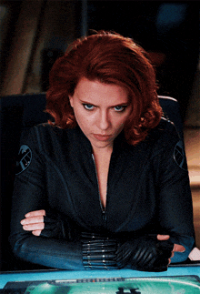 a woman with red hair is wearing a black jacket