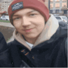 a young man wearing a red beanie and a black jacket