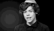 harry styles is wearing a black shirt and making a funny face in a black and white photo .