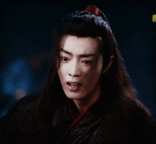 a close up of a man 's face with long hair and a ponytail