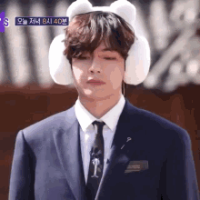 a man in a suit and tie is wearing ear muffs and a pin with a key on it