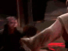 two men are standing next to each other in a dark room and fighting with swords .