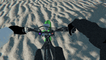 a person riding a green dirt bike on a sandy beach