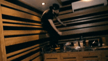a man is jumping in the air in a room with a striped wall