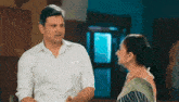 a man and a woman are standing next to each other in a room and talking to each other .