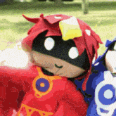 a stuffed animal in a red superhero costume is sitting next to another stuffed animal in a blue superhero costume