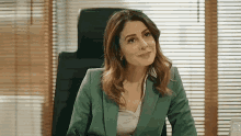 a woman in a green suit is sitting at a desk in an office .