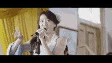 a woman is singing into a microphone while wearing headphones .