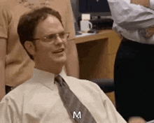 a man wearing glasses and a tie is sitting in an office chair .
