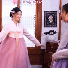 a woman in a pink dress is standing next to a woman in a purple dress