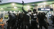 a group of people are dancing in front of a building that says welcome