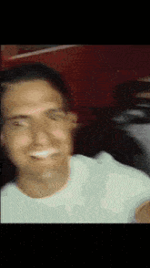 a man in a white shirt is smiling and looking at the camera .