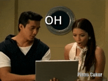 a man and a woman are looking at a laptop with the words oh written on the screen