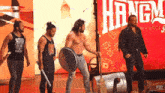 a group of men are standing on a stage in front of a sign that says hang on