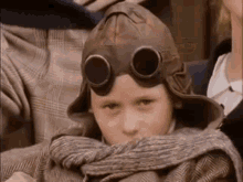 a young boy wearing a hat and goggles is sitting next to a woman .