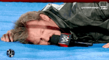 a man laying on a blue mat with a microphone in front of him that says ' totaldivaseps ' on it