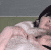 a woman is laying on a bed with her hands on her chest and making a heart shape with her hands .