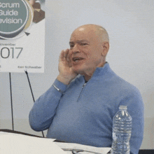 a man sitting in front of a sign that says scrum guide avision